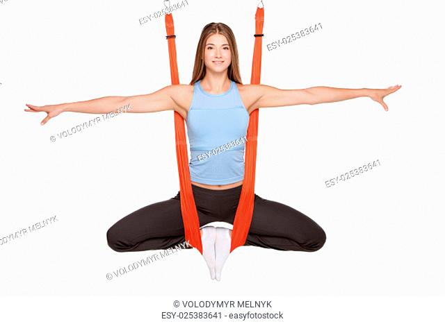 Young woman doing anti-gravity aerial yoga in red hammock on a seamless white background