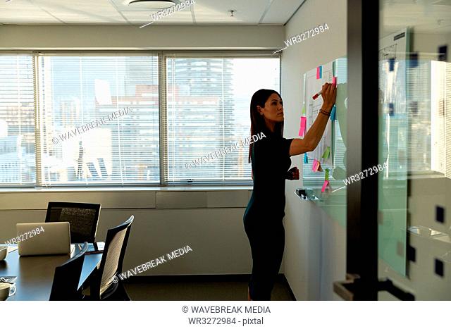 Young female executive writing on sticky notes in a modern office
