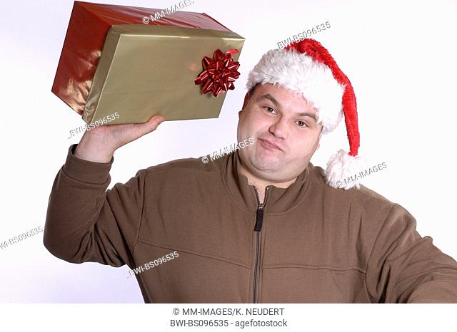 man with Santa's hat holding a Christmas present, Germany