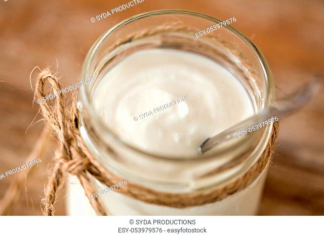 yogurt or sour cream in glass jar on wooden table