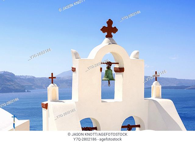 Open belfry of a white church in Oia village overlooking the Aegean Sea, Santorini, Cyclades, Greece