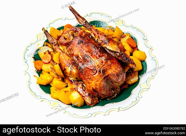 Grilled whole guinea fowl or baked pearl chicken on roasted potatoes and vegetables and port wine sauce is served on a beautiful plate. Clipping path