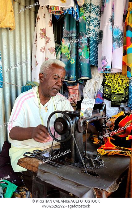 Africa, Ethiopia, Southern Ethopia, Arba Minch, Taylor sitting at his desk and sewing a shirt with his sewing machine