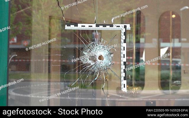 05 May 2022, North Rhine-Westphalia, Duisburg: In the marketplace, a marker is placed on a window next to a bullet hole. Four people were injured in open street...
