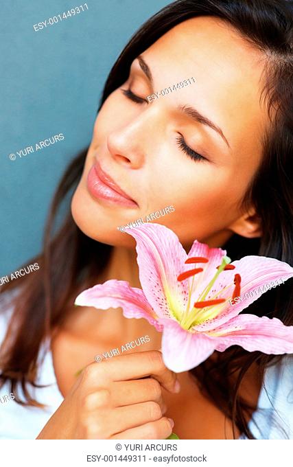 Head shot of pretty woman holding a flower against blue background