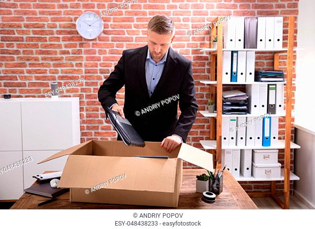 Young Businessman Packing His Belongings In Cardboard Box At Workplace