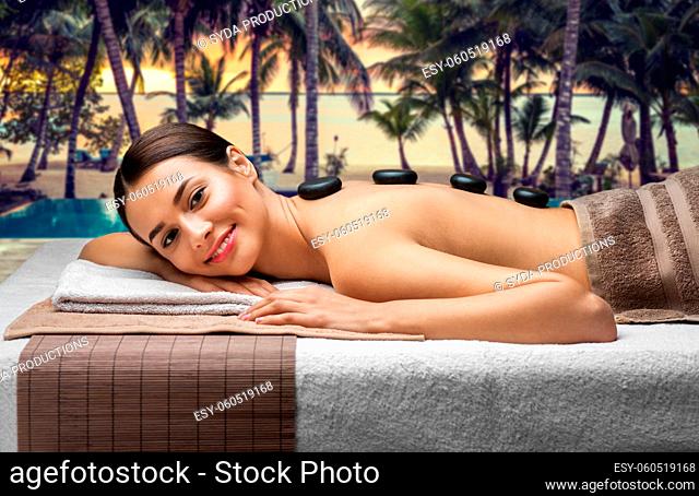 smiling woman having hot stone massage at spa