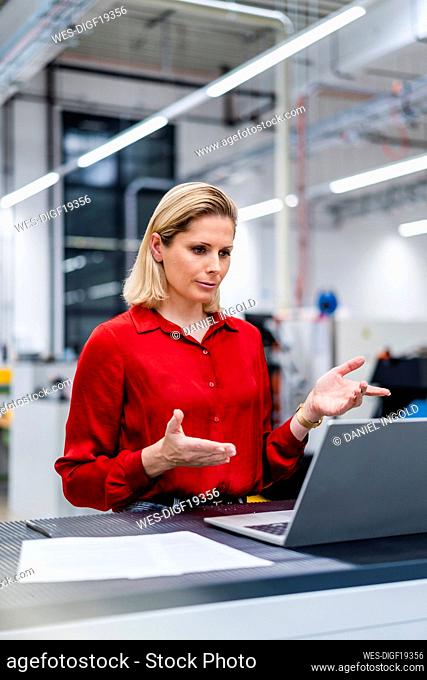 Businesswoman doing video call on laptop at factory