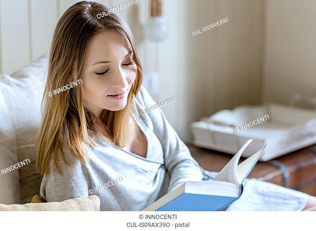 Woman sitting on bed reading book
