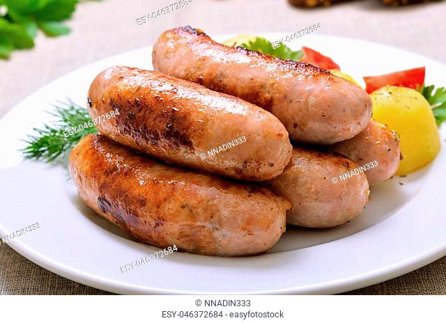 Grilled sausages on white plate, close up view