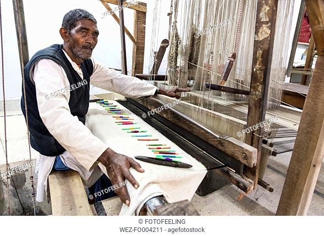 India, Uttar Pradesh, Banaras, Man weaving loom