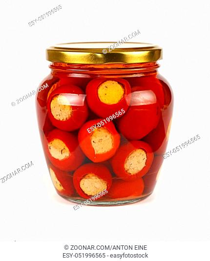 Close up of one glass jar of pickled red hot cherry chili pepperoncini peppers stuffed with soft ricotta cheese, with golden lid over white background