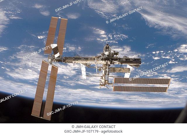 Backdropped by the blackness of space and Earth's horizon, the International Space Station moves away from Space Shuttle Discovery