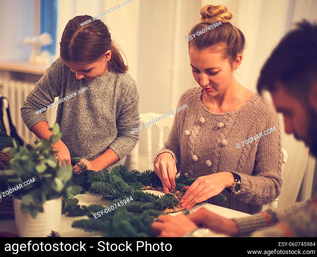 Happy family making an advent wreath with the daughter together