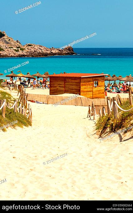 View of the beach and the Mediterranean Sea with visitors and straw sunshades from Cala Agulla on the Spanish holiday island Mallorca