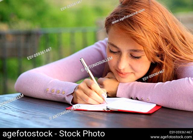 Happy woman writing on paper agenda in a balcony at home or apartment