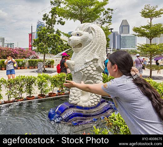 A visitor has her photograph taken beside a Merlion statue, Singapore. The Merlion is an official symbol of Singapore