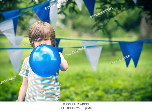 Boy blowing up balloon outdoors