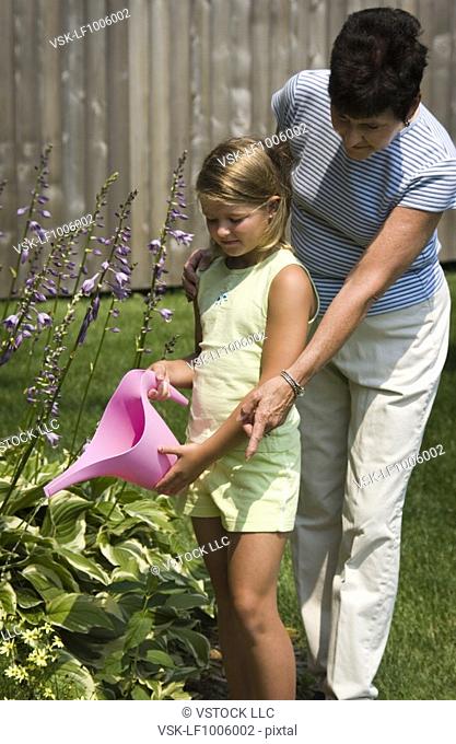 Grandmother and granddaughter watering flowers