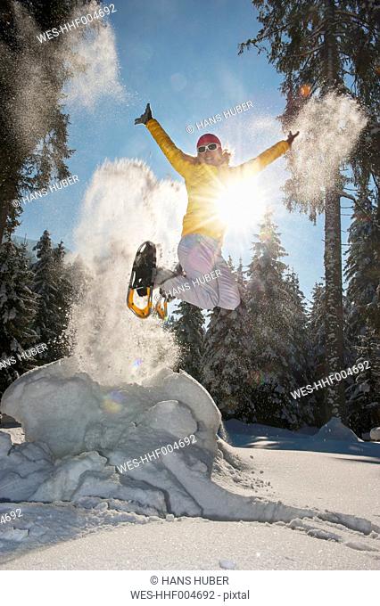 Austria, Salzburg State, Altenmarkt-Zauchensee, Woman with snowshoes jumping in winter landscape