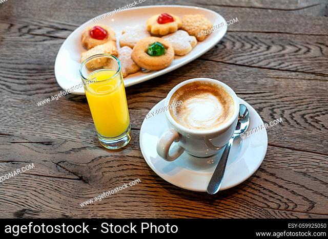 Cup of coffee, butter cookies and orange juice on wooden table