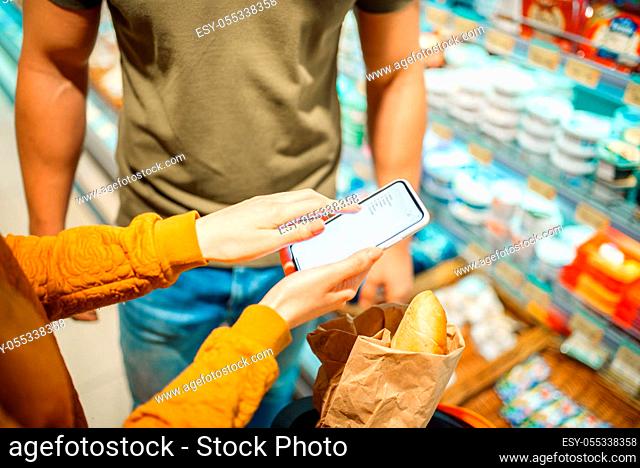 Couple choosing dairy products in grocery store. Male person with cart buying beverages and products in market, customer shopping food and drinks in supermarket