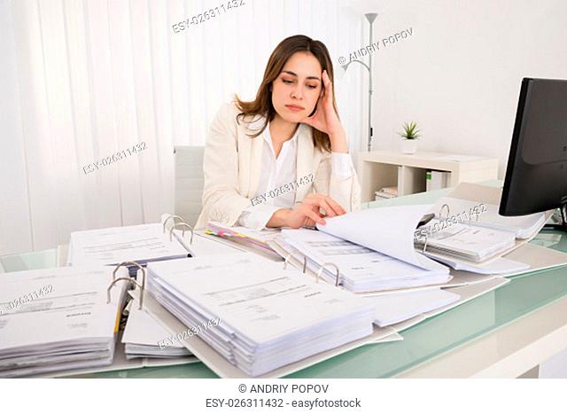 Tired Young Accountant Working With Papers In Office