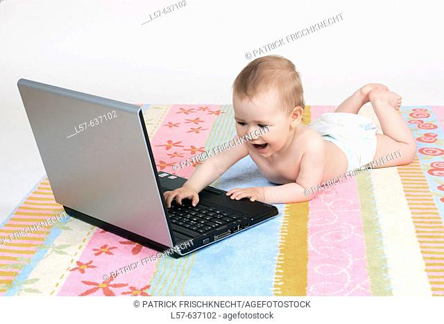 Baby lying on tummy, wearing nappies, playing with laptop computer, Studio, Oetwil am See, Zuerich, Switzerland