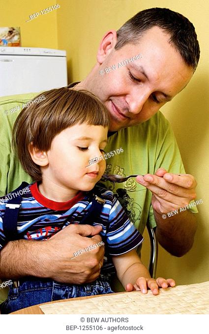 Man giving his son some medicine using a teaspoon