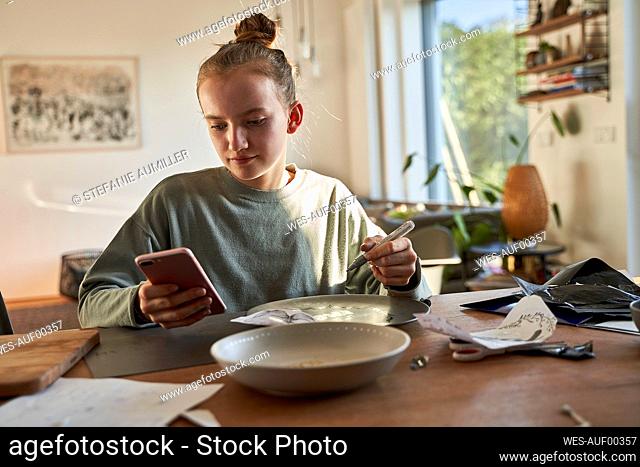 Girl at home using smartphone for a creative online tutorial
