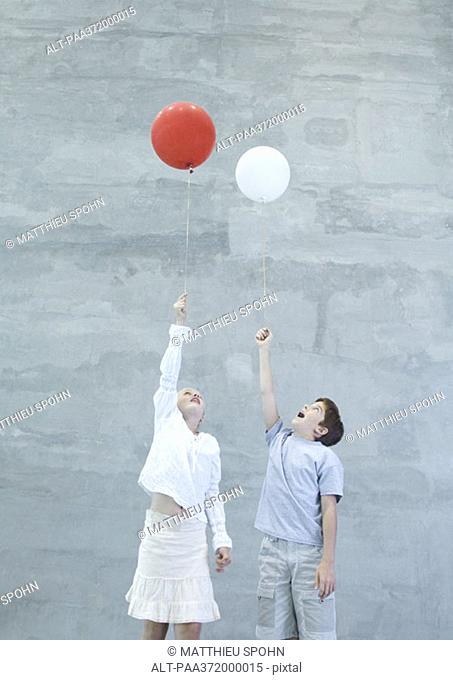 Two children holding helium balloons