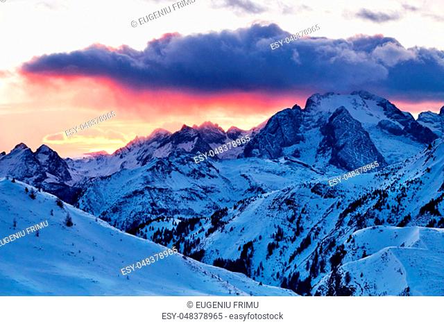 Marmolada mountain peak covered in snow at sunset. Hot red sun. Italy