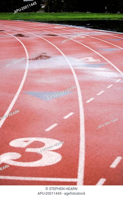 Athletic track lanes at stadium wet with reflection