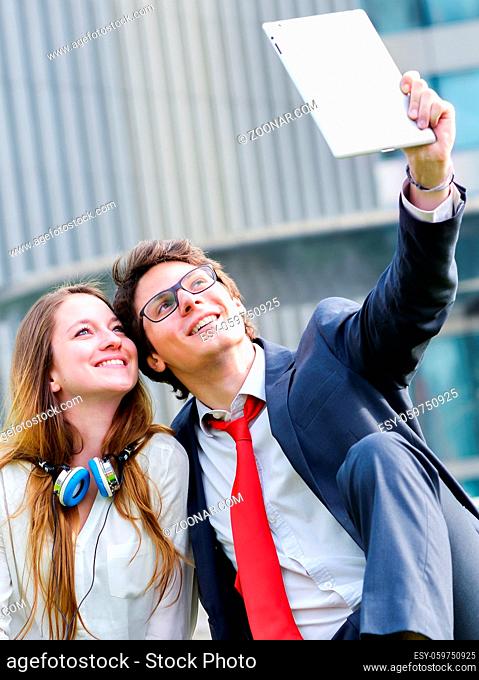 Young Business couple making selfie photo with tablet and buildings on background