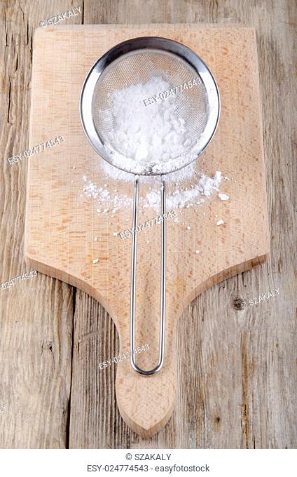 powdered sugar in a small stainless steel sieve on wooden board