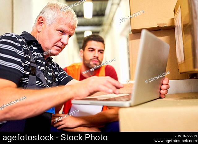 Zwei Lagerarbeiter am Laptop Computer planen Paket Lieferservice im Onlinehandel