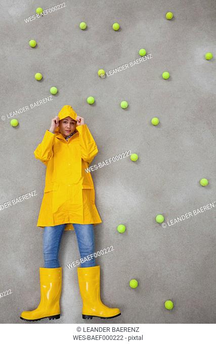Mid adult woman wearing rain coat and rubber boots in acid rain