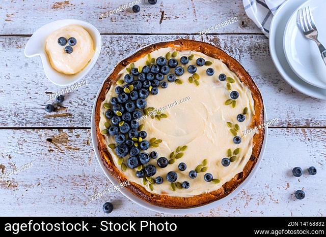 Plate with delicious blueberry cheesecake on white wooden table