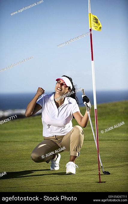 Woman in sportswear holding fist up having goal while playing golf on course