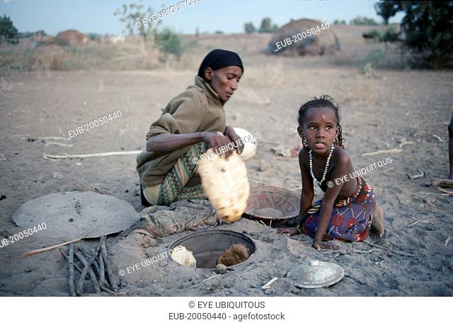 Afar woman and child cooking in oven in ground