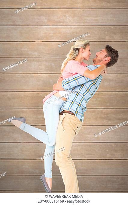 Composite image of handsome man picking up and hugging his girlfriend