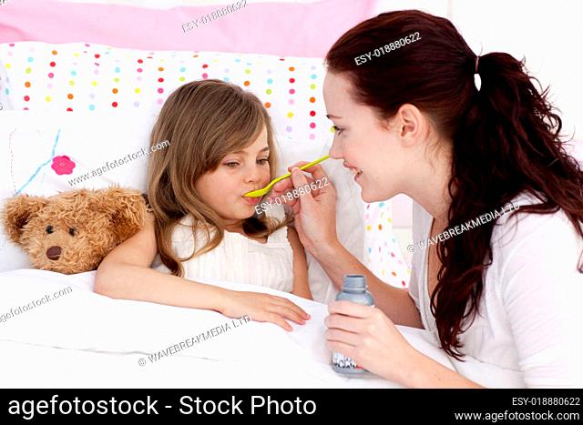 Little girl in bed taking syrup