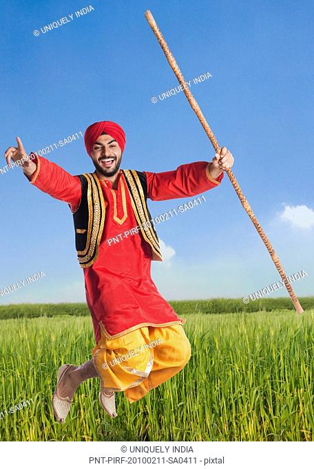 Man doing Bhangra the folk dance of Punjab in India in a field, Gurgaon, Haryana, India
