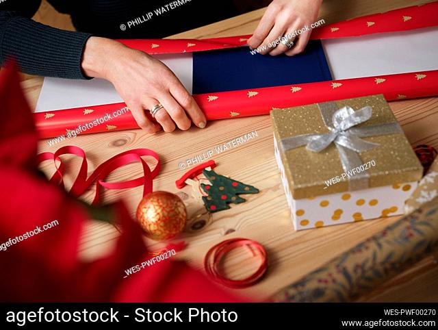 Woman wrapping gift by during Christmas on table