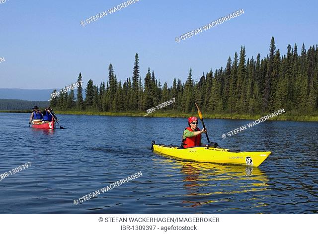 Young woman in kayak, paddling, kayaking, canoe behind, Caribou Lakes, upper Liard River, Yukon Territory, Canada