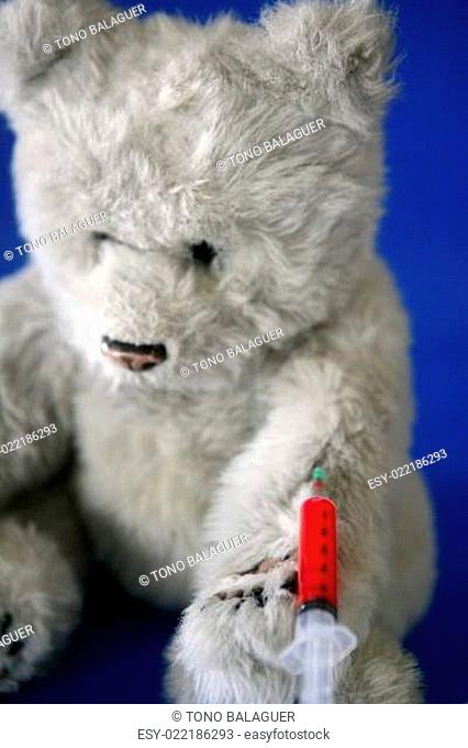 Teddy bear on the doctor, bloody vaccine syringe on its arm