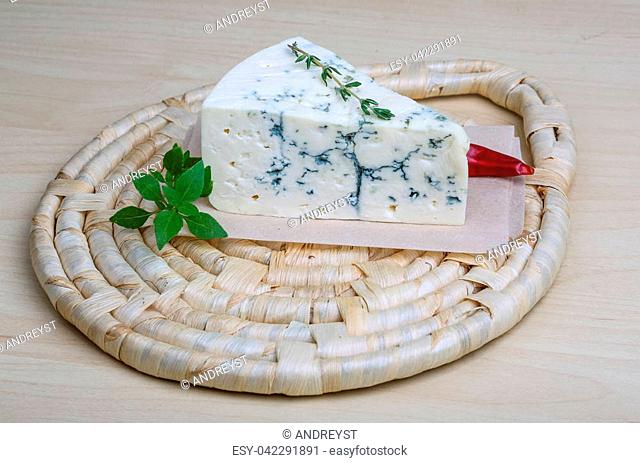 Blue cheese on the wood background with basil leaves