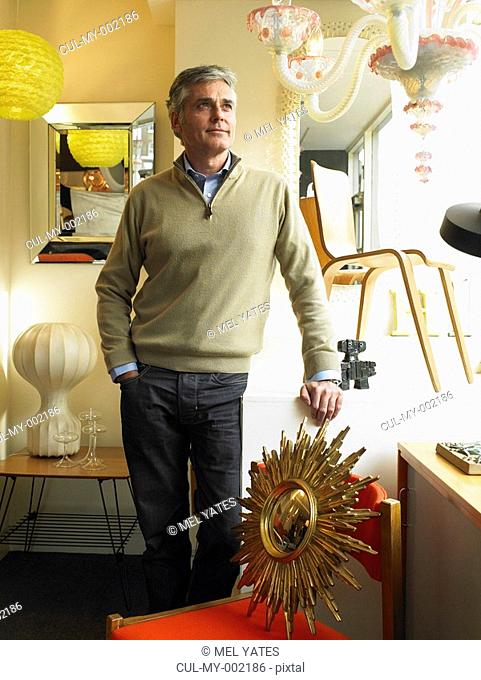 Mature man standing in furniture shop, smiling