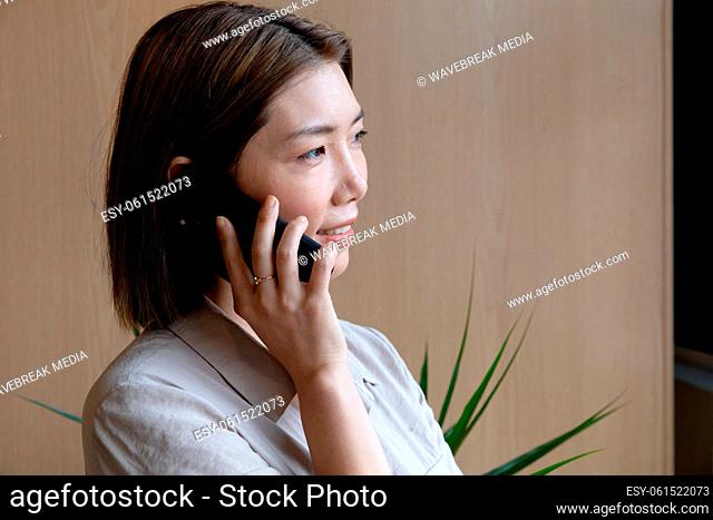 Asian businesswoman talking on smartphone in creative office
