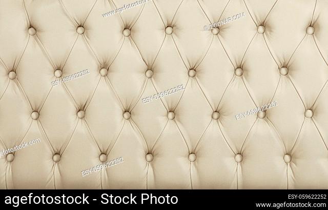Close up background texture of beige white capitone genuine leather, retro Chesterfield style soft tufted furniture upholstery with deep diamond pattern and...